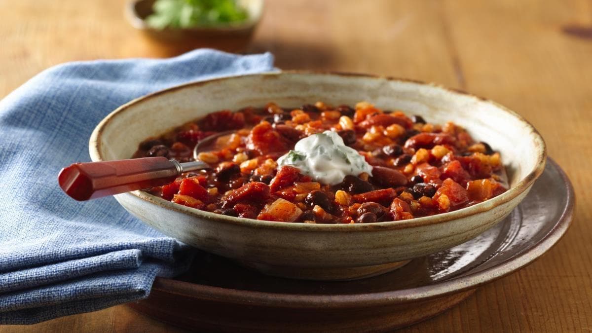 Chili à l’orge et aux haricots avec crème sure à la coriandre